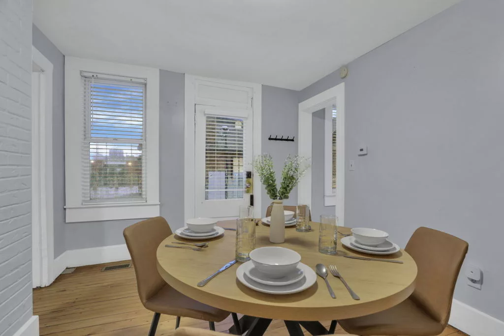 The Lantern dining room with a round table set for four, caramel chairs, and original wood flooring.